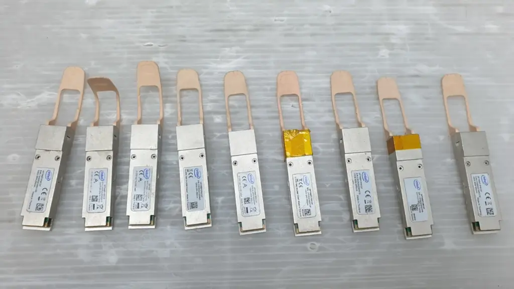 Nine Intel SPTMBP1PMCDF 100G-SR4 QSFP28 transceivers with orange pull tabs, top view