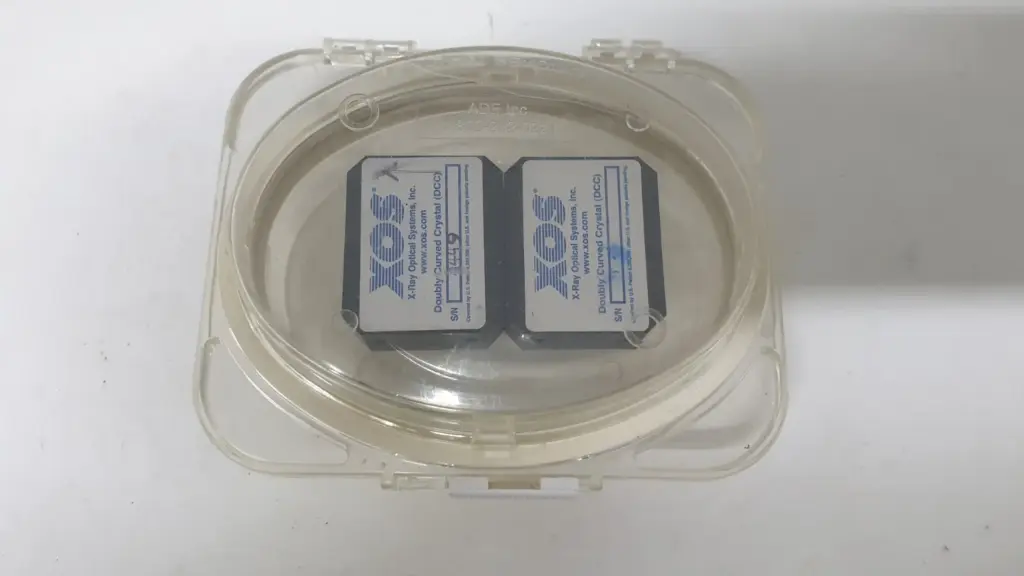 Two XOS doubly curved crystal (DCC) optics inside a clear plastic storage case