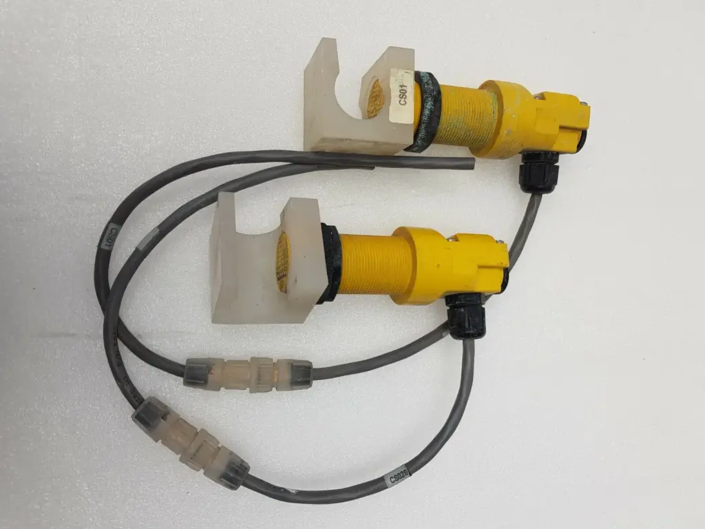 Two Turck BC10-P30SR-VP4X2 yellow proximity sensors in white plastic brackets with grey cables