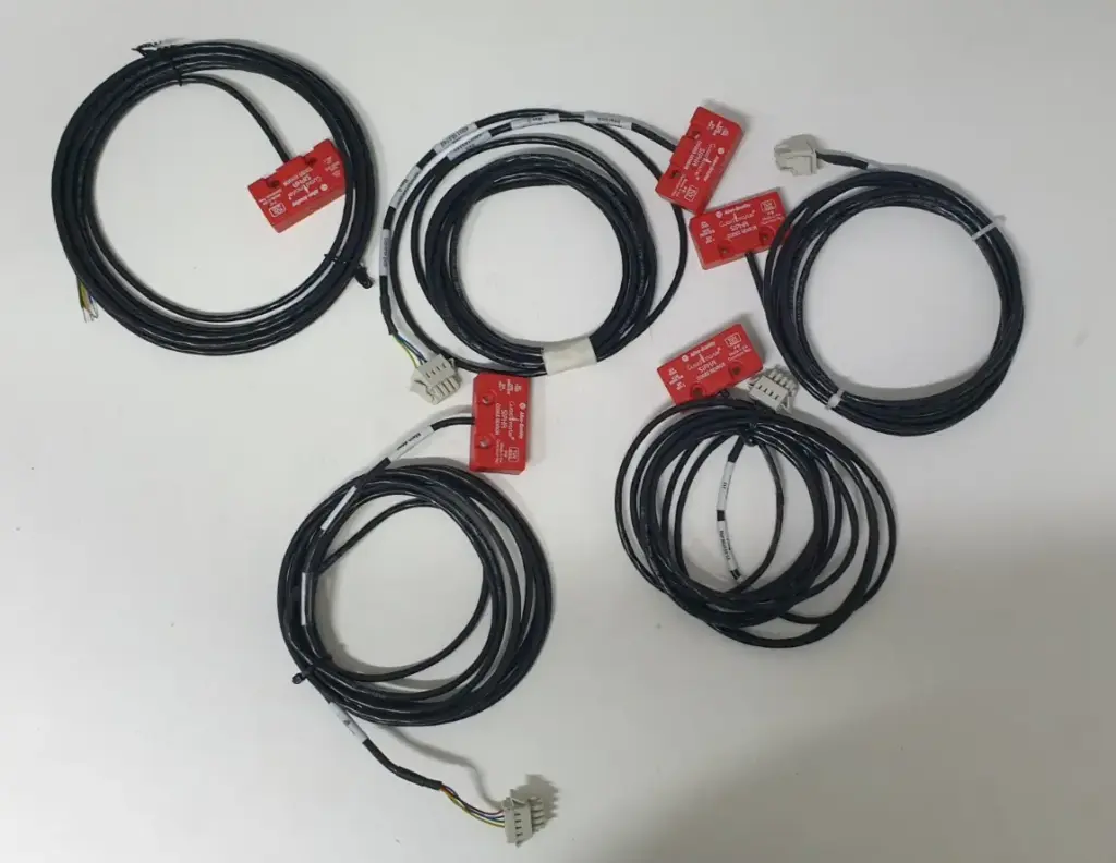 Five Allen-Bradley 440N-S32014 Sipha red coded sensors with coiled black cables