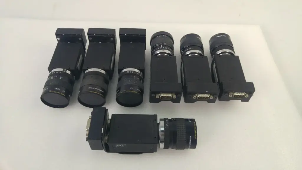 Seven JAI CV-A50 CCD cameras with 6 mm TV lenses and JAI adapter brackets laid out on a table