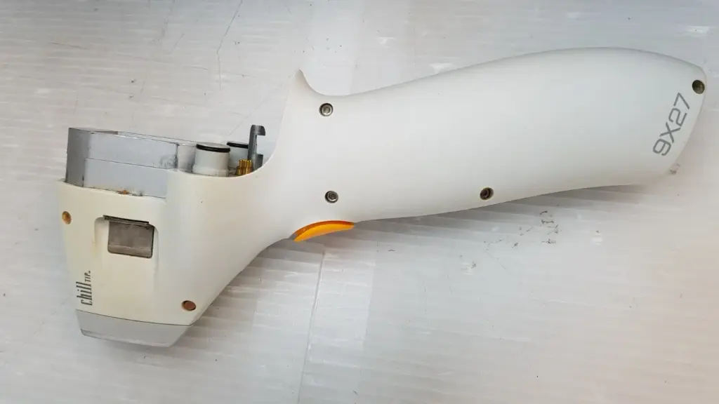 Side of the Lumenis ChillTip handpiece with 9X27 and chill TIP markings and orange button