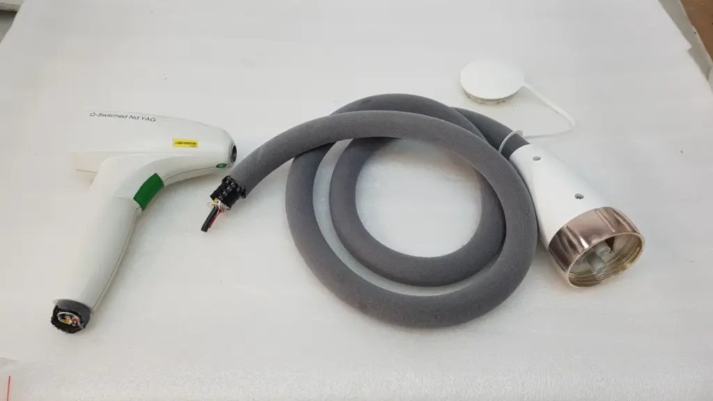 Lumenis Q-Switched Nd:YAG handpiece next to its cut grey umbilical hose and round connector housing