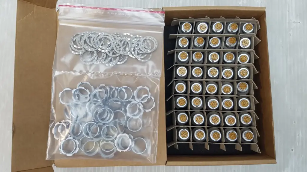 Open box of 40 ODU MINI-SNAP receptacles in a divider tray, with bags of panel nuts and lock washers